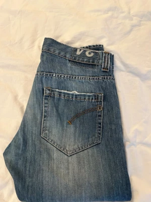 Dondup Jeans - Trendiga Dondup jeans i klassisk blå tvätt med subtila blekningar som ger en modern, stilren look. Jeansen har en snygg passform och passar både till vardag och mer uppklädda outfits. I mycket gott skick utan deffekter. Storlek: 34.  Hör gärna av dig vid frågor!