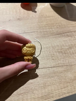 Rare Harry Potter from kinder joy - Säljer en liten guldfärgad figur i plast med glasögon och detaljerat hår. Figuren har ett hål upptill för att fästa en nyckelring eller snöre, perfekt som accessoar till väskan eller nycklarna. Rolig och unik detalj för dig som gillar samlarprylar.