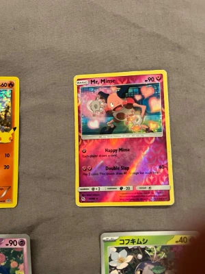 Pokémonkort Mr. Mime holo - Säljer ett Pokémonkort med Mr. Mime som motiv. Kortet har en holografisk effekt och färger i rosa, lila och gult. Texten är på engelska och kortet har 90 HP. Perfekt för samlare eller Pokémonfans.