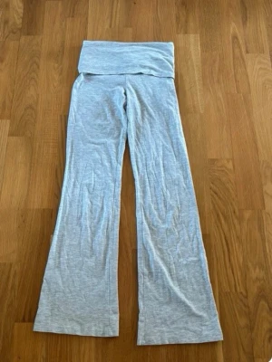 Ljusgrå bootcut yoga pants  - Säljer ett par ljusgrå yoga pants med bootcut-ben och bred linning. Mjukt och stretchigt material som sitter skönt på kroppen. Perfekta för en avslappnad och trendig look.