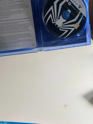 Marvel's Spider-Man 2 PS5 spel - Säljer Marvel's Spider-Man 2 till PlayStation 5. Spelet kommer i ett blått plastfodral med snyggt omslag där både Peter Parker och Miles Morales syns. Skivan har en svartvit spindel-logga. Perfekt för dig som gillar action och superhjältar!