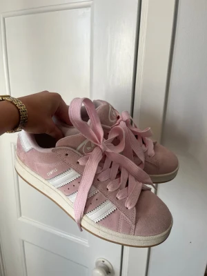 Adidas Campus rosa sneakers - Adidas Campus sneakers i ljusrosa mocka med vita detaljer och breda rosa skosnören. Använda några gånger och har därför några små fläckar. 