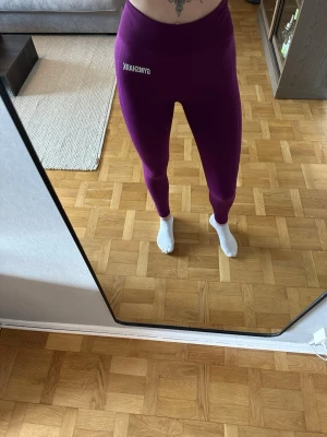 Lila träningstights från Gymshark - Säljer ett par snygga lila träningstights från Gymshark med hög midja. Använd endast ett par gånger. Står ingen storlek men troligen XS/S. Jag är 168cm