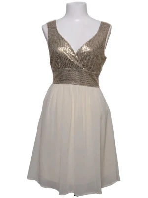Vit kortklänning med paljetter - Snygg vit kortklänning med glittrig, guldpaljettprydd överdel och omlottdesign. Kjolen är lätt och luftig i chiffongliknande material. Ärmlös modell med v-ringning både fram och bak. Perfekt för dig som vill sticka ut lite extra.