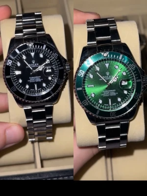 Rollie 2x - Snygg Submariner med klassisk svart urtavla och vridbar bezel. Klockan har en robust länk i rostfritt stål och tydliga indexmarkeringar. Perfekt för dig som gillar tidlös design och exklusiv känsla. Automatisk rörelse och datumfönster vid 3-positionen. Om du vill köpa 1x besök andra annonsen under profilen.