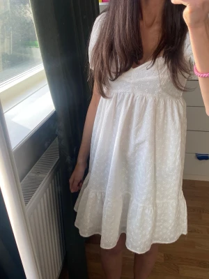 Vit kort klänning med puffärm - Söt vit kortklänning med puffärmar och broderade. Har bara använt 2 gånger den är i storlek S men den passar XS