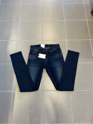 Mörkblå tiger of sweden jeans W29 L32 - Snygga mörkblå slimmade jeans med klassisk femficksdesign och smal passform. Jeansen har en stilren look med subtila slitningar och kontrastsömmar. Perfekta för dig som gillar en modern och enkel stil. Perfekta nu för tidig vår. Kostar 1300kr nya 