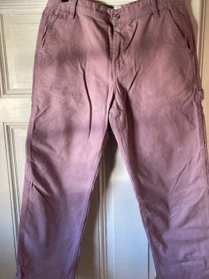 Ljuslila cargobyxor lose fit  - Säljer ett par ljuslila cargobyxor i bomull med raka ben och flera praktiska fickor. Byxorna har bälteshällor, knappgylf och en avslappnad passform. Perfekta för dig som gillar streetwear och vill ha något unikt i garderoben.