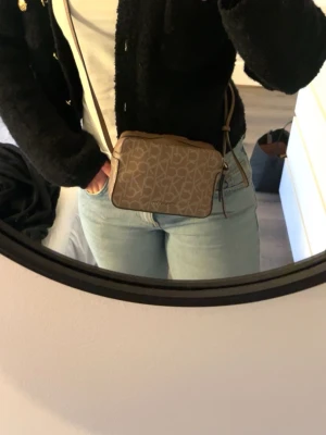 Beige axelväska från Calvin Klein - Justerbara band i längd. Väskan är äkta Calvin Klein. Defekter på sista sidan (därav priset).