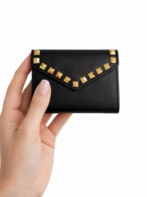 Plånbok i läderimitation med guldnitar  - Stilren plånbok tillverkad i veganskt läder med handgjorda nitar och egendesignade detaljer. Plånboken är vikbar och stängs med knapp. Plånboken rymmer flera kort och har praktiska fack som gör den både funktionell och stilren – samtidigt som den ger din outfit en extra touch.  Storlek: 9 × 11 cm 💌 