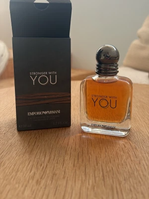 Emporio Armani Stronger With You EdT - Emporio Armani Stronger With You är en Eau de Toilette med en elegant glasflaska och rundad metallkork. Doften har en varm bärnstensfärgad ton och flaskan rymmer 50 ml. Förpackningen är svart med stilren text och bruna detaljer.