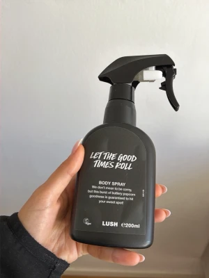 Lush Let The Good Times Roll Body Spray - En svart sprayflaska med Lush Let The Good Times Roll body spray, 200 ml. Doften har inslag av smörig popcorn och är vegansk. Flaskan har en modern, matt finish och är enkel att använda med sitt spraymunstycke. Använd ett fåtal gånger bara säljer pga gillade inte doften alls.