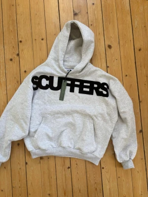 Scuffers hoodie - Snygg grå hoodie från Scuffers med stor svart logga över bröstet. Storlek S, helt ny med prislappen kvar! 