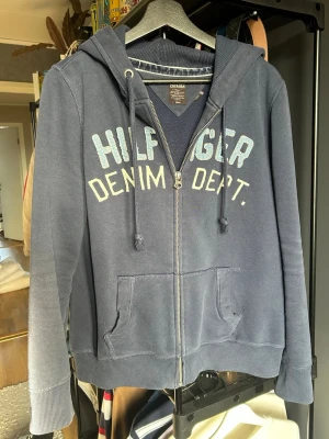 Vintage Tommy Hilfiger Zip-up Hoodie - Säljer en riktigt fet Tommy Hilfiger Denim Department zip-up hoodie! Hoodien har en snygg tvätt och cool denimlook på bokstäverna.  •Storlek M och sitter lite tajt om armarna.  •Mått: Bredd≈54cm, Längd≈60cm •Väldigt bra skick  Skicka en fråga om du undrar något så svarar jag så fort som möjligt🐦‍🔥