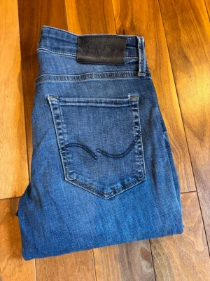 Jack & Jones Slim(Glenn) jeans - Säljer ett par snygga mellanblå Jack & Jones  jeans  Märke: Jack & Jones  Storlek: W30 L30  Färg: Mellanblå / Denim  Passform: Slimfit(Glenn)  Dessa klassiska blå denimjeans från Jack & Jones erbjuder både komfort och stil. De har en snygg tvätt som ger en tidlös känsla, perfekt för en avslappnad vardagsstil med sneakers och en tröja.  Skick: Bra använt skick - ett design hål men inga större skador, endast normalt slitage.  Hör av dig vid intresse!