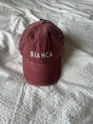 Stentvättad keps  - Snygg stentvättad keps med vit brodyr framtill där det står 'BIANCA' och på baksidan 'Coca-Cola'. Klassisk böjd skärm och justerbar rem baktill. Aldrig använd 