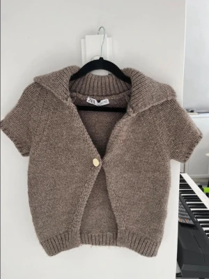 Brun stickad kortärmad kofta från ZARA - En jättefin brun kortärmad kofta från Zara. Använd fåtal gånger. Storlek S