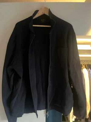 Svart overshirt med dragkedja - Stilren svart overshirt från Massimo Dutti med två bröstfickor och hel dragkedja framtill. Jackan har en rak passform och är tillverkad i ett mjukt material som passar perfekt för lager på lager. Enkel och clean design som funkar till det mesta.