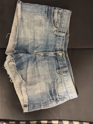 Ljusblå jeansshorts med rå kant - Säljer ett par lågmidjade ljusblå jeansshorts. De är i bra skick. Det står ingen storlek men skulle säga att de är storlek 40