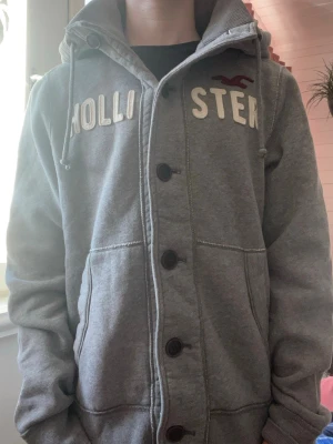 Grå hoodie från Hollister med knappar - Säljer denna gråa hoodie från Hollister. Modellen är 174| 65kg bär storlek S. Skriv vid frågor✨