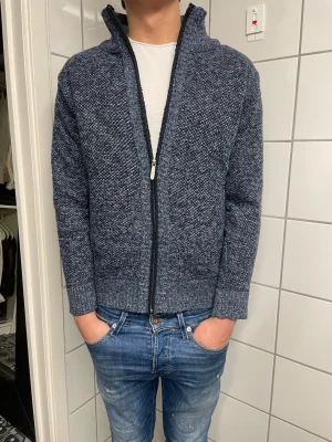 Mörkblå stickad ziptröja - Säljer en mörkblå stickad ziptröja med hög krage och grovstickad struktur. Storlek S. Tröjan har dragkedja framtill, två fickor och ribbade muddar vid ärmslut och nederkant. Perfekt för lager-på-lager. Hör av dig vid funderingar!😁