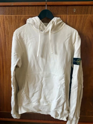 Vit hoodie från Stone Island - Säljer en stilren créme färgad hoodie från Stone Island med klassisk huva och dragsnören. Säljer eftersom den är för liten för mig