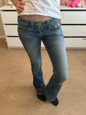 True Religion blå bootcut jeans skicka gärna förfrågan om ni vill föreslå ett pris🩷 - Snygga blå bootcut jeans från True Religion med låg midja och klassiska kontrastsömmar. Jeansen har dekorativa fickor med knappar och broderade detaljer på bakfickorna.  Gylfen är sönder men kan lagas 
