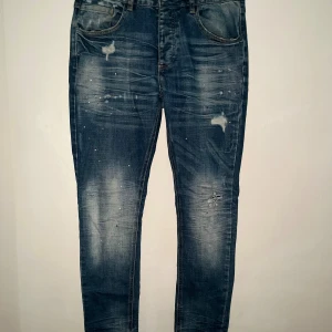 Blåa jeans Alessandro Zavetti - Snygga blå skinny jeans från Alessandro Zavetti med slitningar och färgstänk för en cool, trendig look. Jeansen har klassisk femficksdesign, normal midja och är tillverkade i stretchig denim för skön passform.