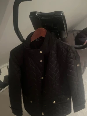 Svart quiltad jacka från Ralph Lauren - Snygg svart quiltad jacka från Ralph Lauren med tryckknappar och ståkrage. Jackan har diskret logga på ärmen och fickor framtill med knappdetaljer. Perfekt för dig som vill ha en stilren och tidlös look. Pris kan diskuteras 