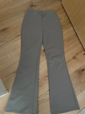 Grå bootcut byxor - Snygga grå bootcut byxor med hög midja och stilren design. Perfekta för dig som vill ha ett trendigt och bekvämt plagg som passar till många olika outfits. Materialet känns mjukt och följsamt mot kroppen.