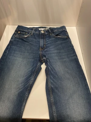 Klassiska blå jeans med raka ben - Snygga blå jeans i klassisk modell med raka ben och fem fickor. Jeansen har en medelhög midja och tydliga sömmar. Perfekta för en avslappnad och trendig look. Materialet är denim i bomull.