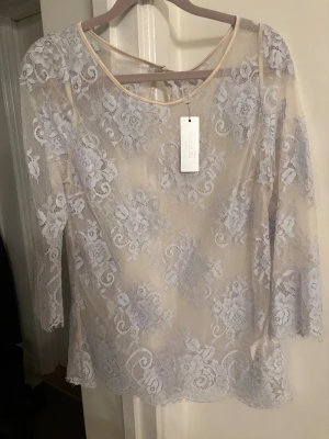 Vit spetsblus med trekvartsärm - Säljer en elegant vit spetsblus från Vero Moda med blommigt mönster och rund halsringning. Blusen har trekvartsärmar och transparent spetsmaterial som ger en romantisk vibe. Perfekt att styla med jeans eller kjol för en trendig look.