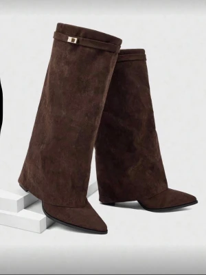 Bruna mockastövlar med spetsig tå - Unika bruna stövlar i mocka med bredt skaft och spetsig tå. Stövlarna har en elegant design med dekorativt band upptill och låg klack. Perfekta för dig som vill sticka ut med din stil.