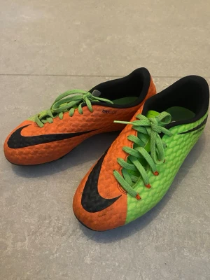 Nike Magista orange/gröna fotbollsskor - Säljer ett par Nike Magista fotbollsskor i en riktigt fet färgkombination av orange och grönt med svarta detaljer. Skorna har snörning, mönstrad ovandel och fasta dobbar för bra grepp på planen. Perfekta för dig som vill sticka ut på matchen!