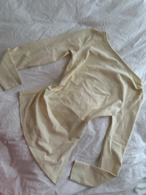 Ljusgul långärmad topp - En enkel och stilren ljusgullångärmad topp i mjukt material. Toppen har en klassisk passform och rund halsringning, perfekt att matcha med olika outfits. Passar dig som gillar minimalistisk och clean stil.