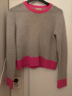 From future tröja - Säljer en snygg grå stickad tröja med rosa detaljer ifrån from future