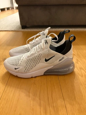 Nike Air Max 270 vita/svarta - mycket bra skick  - Nike Air Max 270 i mycket bra skick. Skorna är väldigt lite använda och ser nya ut på ovansidan. Endast lite missfärgning på sulans undersida från användning. Annars rena och fräscha. Säljs eftersom de inte används längre. Säljs utan orginalkartong. Storlek: 44 Frakt: Fraktas omgående dagen då köpet görs eller dagen efter. Serienummer: AH8050-100