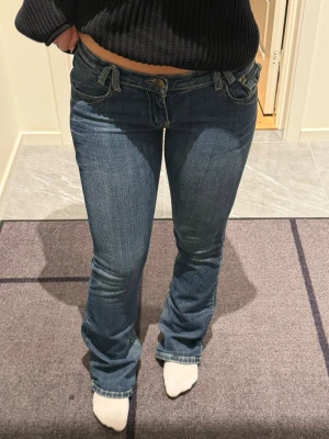 Lågmidjade jeans  - Snygga blå bootcut jeans från D&G med låg midja och klassiska detaljer. Jeansen har dekorativa fickor bak med knapp och logga på läderpatch i midjan. Tillverkade i slitstark denim med lätt tvättad look och kontrastsömmar. För dig som älskar lågmidjat! Jag är 160 cm 