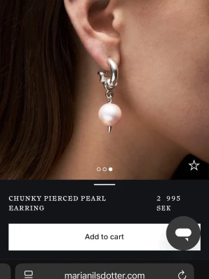 Chunky pierced pearl örhänge - Chunky pierced pearl örhänge från Maria Nilsdotter i silver med en stor vit pärla och en spetsig detalj längst ner. Örhänget har en unik och edgy design med robust silverring och hängande pärla som ger ett coolt statement.