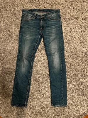 Blå slim fit jeans från Nudie Jeans - Säljer ett par riktigt feta nudies med slitningar. De är i storlek W27 L30 som passar runt 165/167! 👍tveka inte att fråga om extra bilder och priset är ej hugget i sten! 🙌