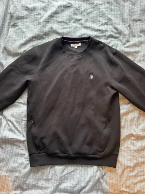 Svart sweatshirt från U.S. Polo Assn. - Helt ny och oanvänd tröja från US Polo Assn. fick den i julklapp men var för stor. Tröjan är i storlek M och är somsagt helt oanvänd och har inga fel eller skador. (Nypris är 700kr)