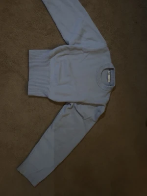 Ljusblå stickad tröja från ZARA - Snygg ljusblå stickad tröja från ZARA med rund halsringning och breda ribbade muddar vid ärmslut och midja. Enkel och stilren design som passar perfekt till jeans eller kjol.