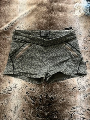 Leopardmönstrade shorts med dragkedjor - Snygga shorts från Bershka med leopardmönster i grå och svart. Modellen är högmidjad med två dragkedjefickor framtill och dekorativa sömmar. Perfekta för dig som vill sticka ut lite extra i sommar!