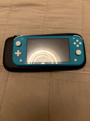 Nintendo Switch Lite med fodral - Säljer en blå Nintendo Switch Lite tillsammans med ett svart skyddsfodral. Konsolen har vit styrspak och knappar, och fodralet är i tåligt material med Nintendo Switch-loggan på framsidan. Perfekt för gaming på språng eller hemma. Det kommer med en laddare 
