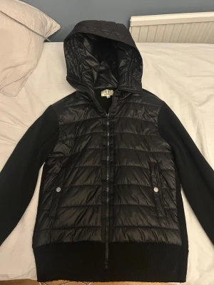 Svart cardigan  från Elegance Essentials - Snygg svart cardigan från Elegance Essentials. Jackan har dragkedja, två fickor med tryckknappar. Perfekt för vår dagar och ger en modern look. Nypris 1100kr, andvänd fåtal gånger.