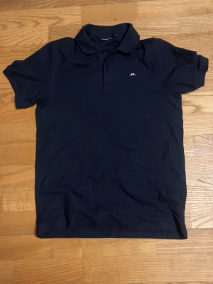 Mörkblå piké från J.Lindeberg - Säljer denna nästan helt nya J.Lindeberg piken.  Använd typ 2 gånger! Skriv vid frågor!