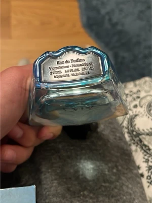 Blå Eau de Parfum sprayflaska  - Snygg Eau de Parfum i en blå glasflaska med metallisk etikett undertill. Flaskan har en modern, stilren form och rymmer 90 ml. Passar perfekt för dig som gillar exklusiva dofter och vill ha en elegant parfymflaska i badrumshyllan.