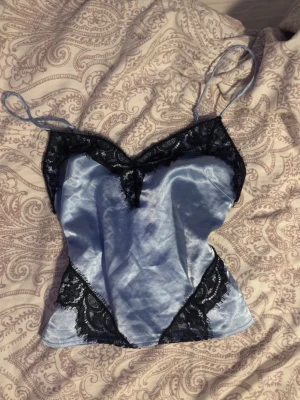 Spetstopp med satin - En jättefin topp från H&M med spetsdetaljer!💕 bra kvalitet då jag inte har använt den då den är för liten, är i storlek xs men skulle säga xxs för den är ganska tajt🤍 om ni är osäkra fråga gärna om mått!