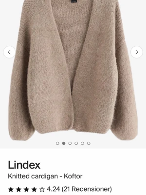 Beige stickad kofta från Lindex - Mysig beige stickad kofta från Lindex  med  v-ringning. Koftan har långa ärmar och är tillverkad i ett mjukt, fluffigt material som ger en avslappnad look. Perfekt att slänga på sig när det är kyligt ute. Använd fåtal gånger