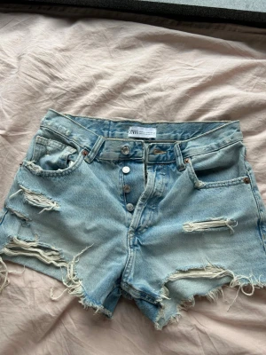 Jeansshorts från Zara - Ett par ljusblåa jeansshorts från Zara i storlek 34. Använda men finns inga defekter 
